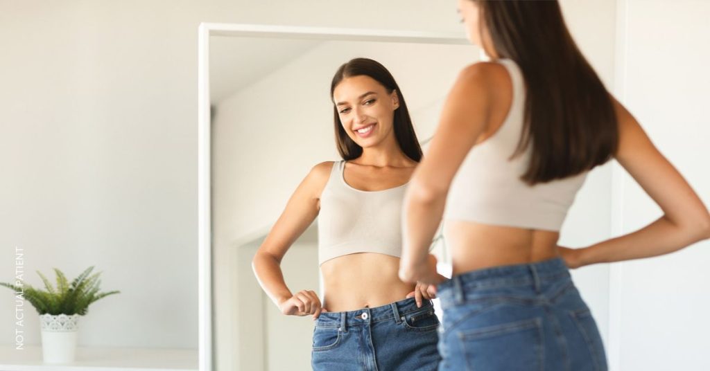 Woman with dark hair is admiring at her reflection in the mirror (NOT ACTUAL PATIENT)