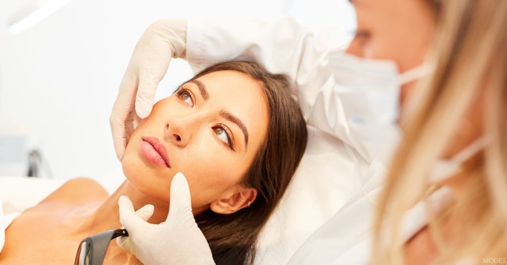 A beautiful woman with glowing skin is having her face examined by a doctor. (Models)